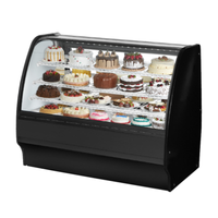 Refrigerated curved glass bakery display case showcasing a variety of cakes and desserts in an elegant setting.