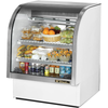Curved glass deli merchandiser showcasing fresh salads, sandwiches, drinks, and fruits in a stylish display unit.