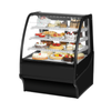 Curved glass bakery merchandiser showcasing a variety of delicious desserts and pastries in an elegant display.