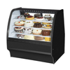 Curved glass bakery merchandiser showcasing a variety of cakes and pastries in an elegant display.